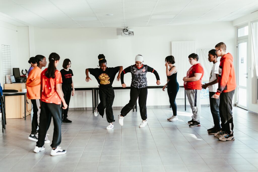 une danseuse et des élèves danseurs autour d'elles apprennent un mouvement de danse